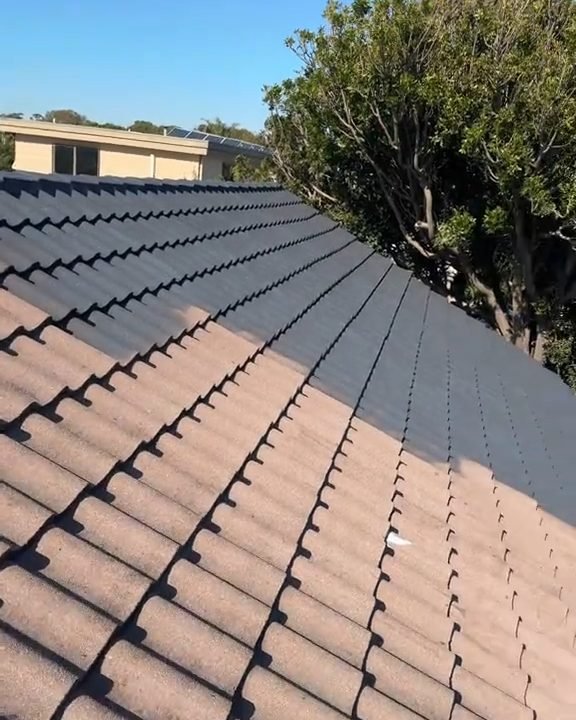 A tiled roof half coated: dark coated tiles beside the tiles still to do